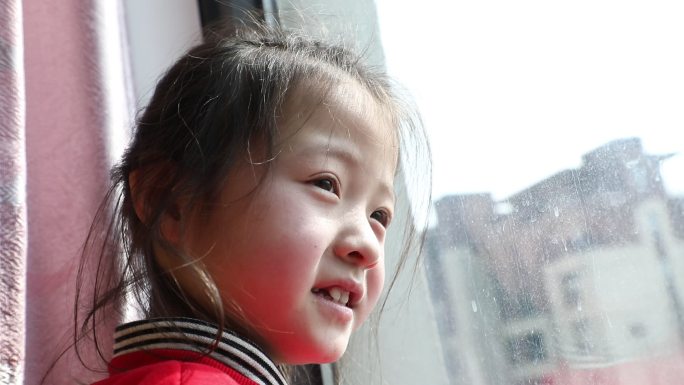 小女孩望向窗外期盼样子