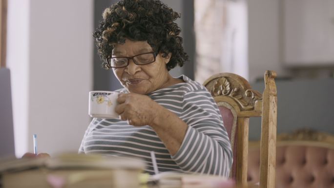 一名年长女性坐在家中使用笔记本电脑