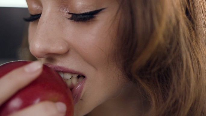 年轻女子吃着新鲜的红苹果