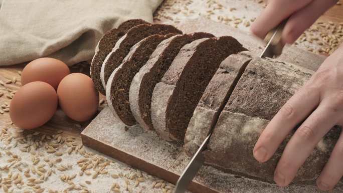 在木制砧板上切面包。