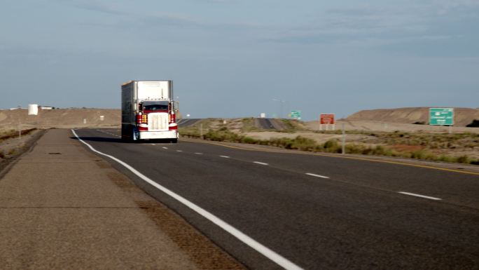 一辆长途半卡车沿着沙漠中的四车道公路行驶