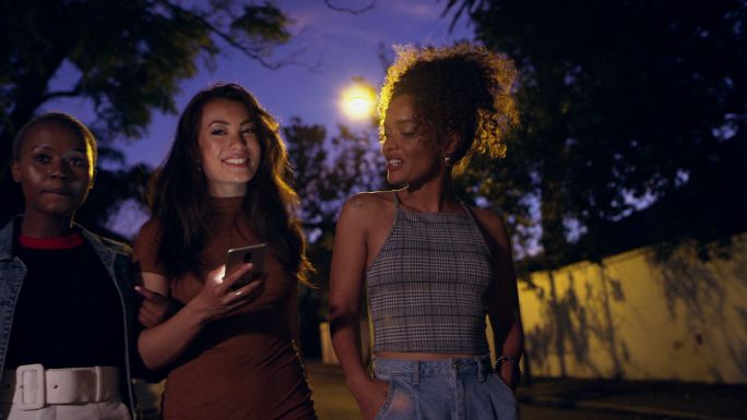 三个朋友在夜间外出散步时使用手机