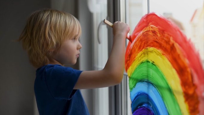 小男孩在窗户上画彩虹
