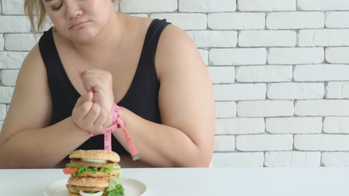 女孩的手被束缚以禁止食用垃圾食品