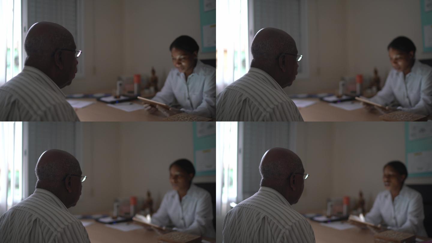 女医生使用数字平板电脑与老年患者交谈