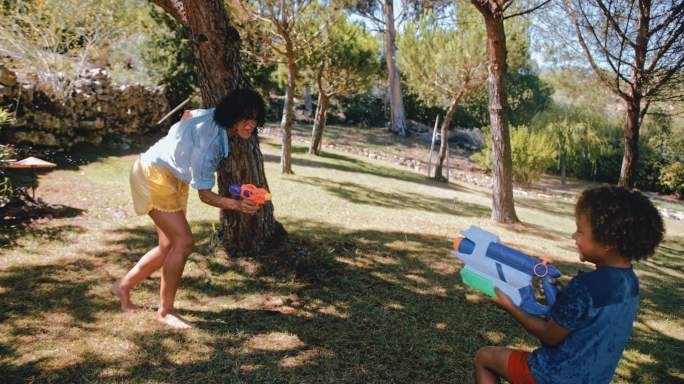 母亲和小男孩在花园里用水枪打架