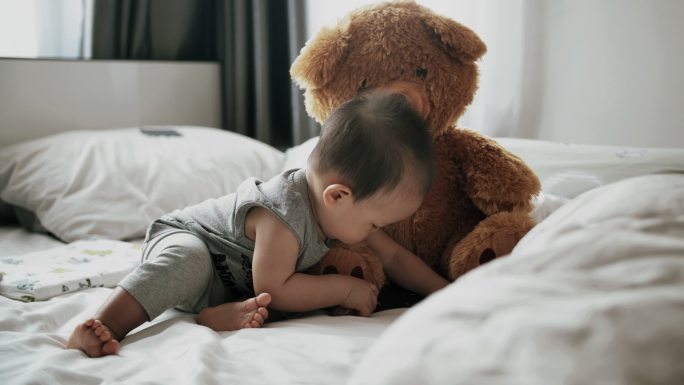 小男孩在家玩柔软的泰迪熊玩具