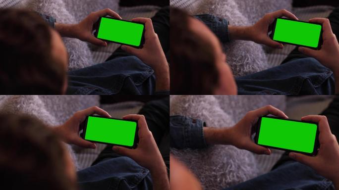 男人拿着手机水平地看着绿色屏幕