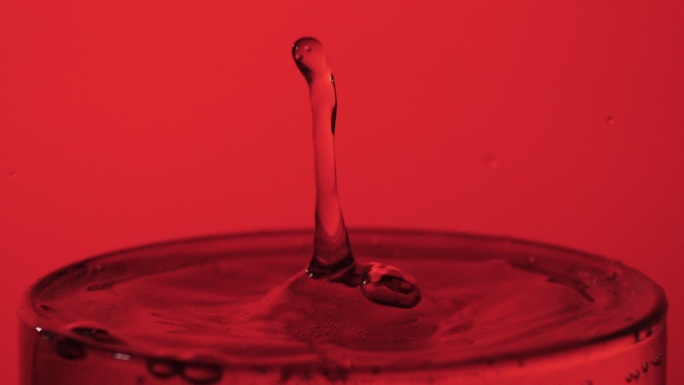 水滴落在装满水的玻璃杯里，特写，慢镜头