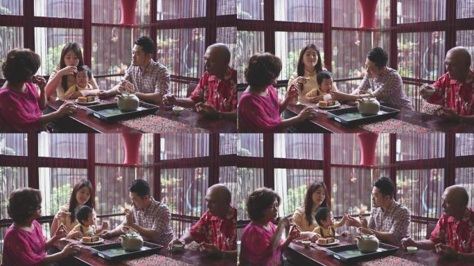 一家人在家里享用传统的中秋月饼和中国茶