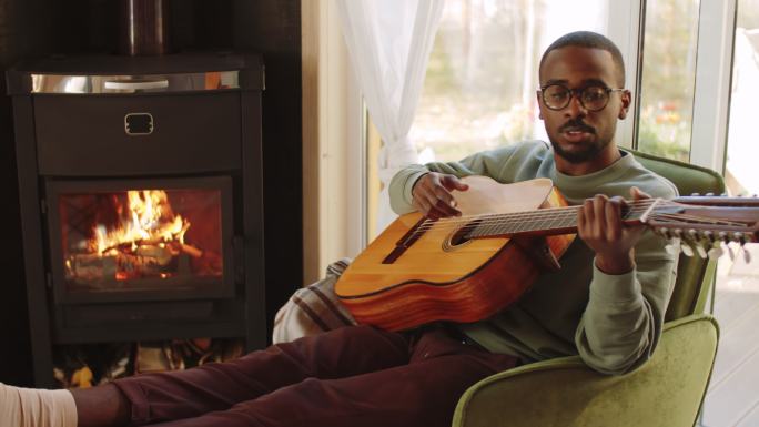 美国黑人男子在家壁炉旁弹吉他
