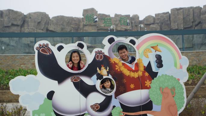 父母和孩子在动物园熊猫馆拍合影