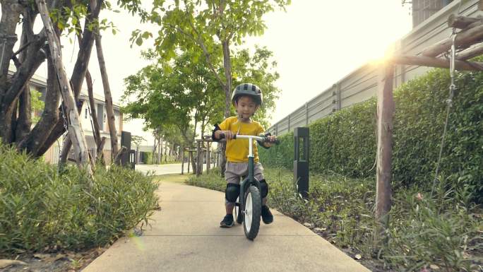 一个小男孩在公园外面骑自行车