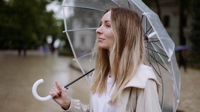 金发女人在雨天打开透明雨伞