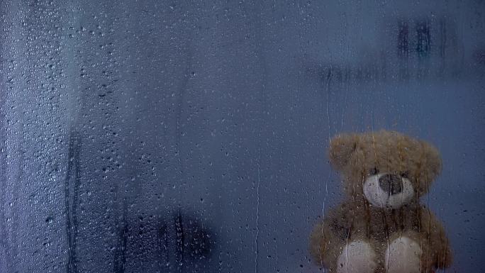 泰迪熊在孤儿院雨窗后的窗台上