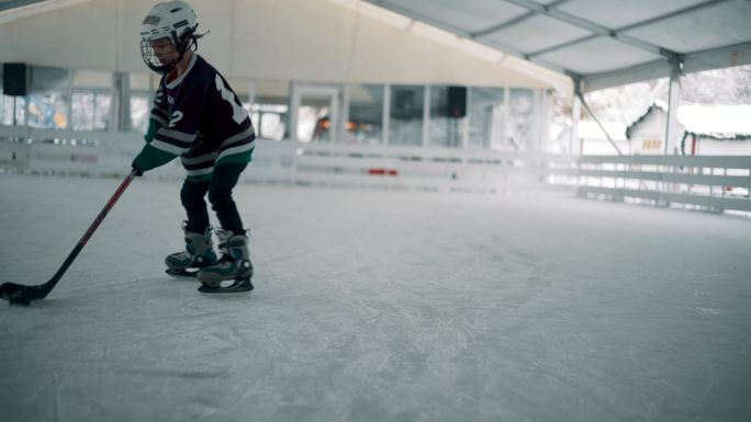 在溜冰场打冰球的小男孩
