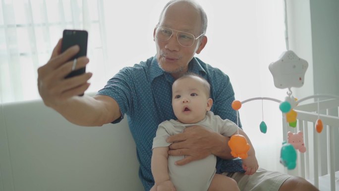 祖父在智能手机上与可爱的男婴自拍