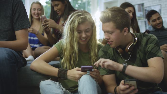 一群青少年在智能手机上分享东西。