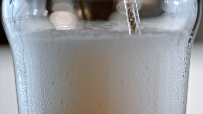 啤酒被倒入酒杯中，产生气泡。