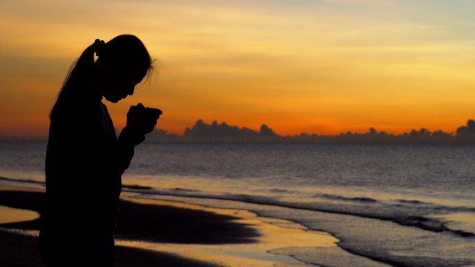 日落背景下祈祷的女人