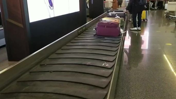 航班旅客拿行李箱手提箱旅行李箱传送站台