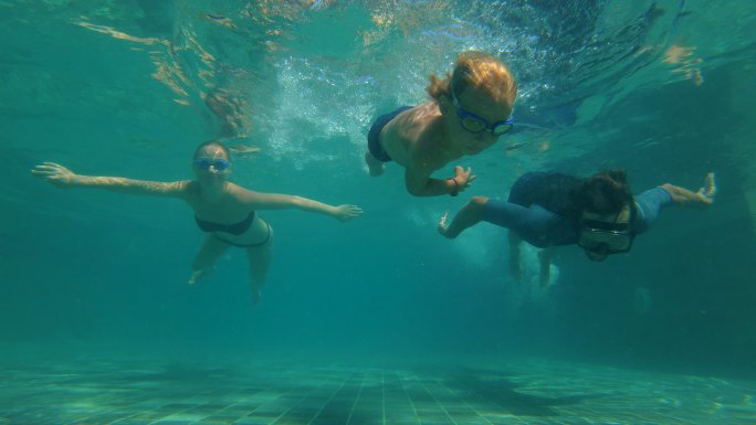 一个快乐的家庭在游泳池里潜水