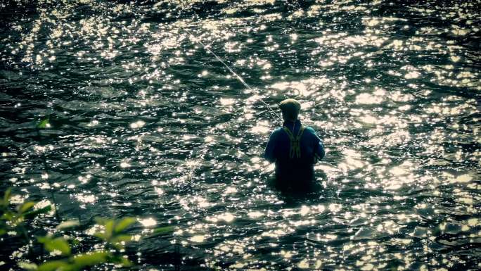 男人在齐腰深的水中钓鱼