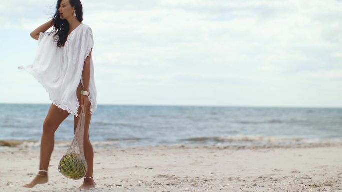 在户外海滩上拿着西瓜的女人