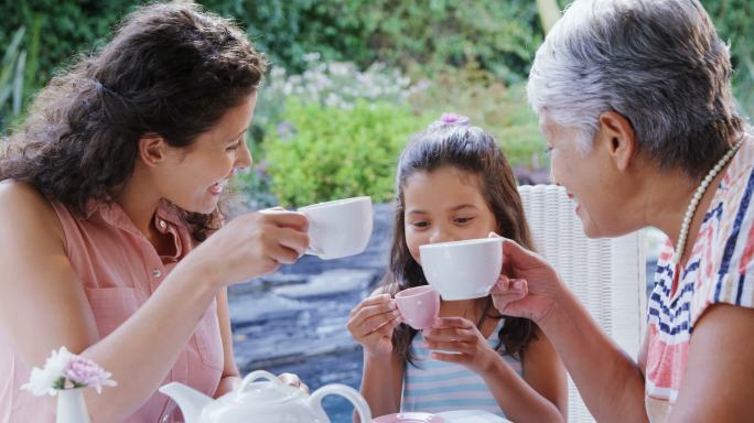 妈妈、女儿和奶奶在花园里喝茶