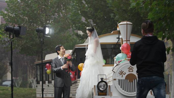 年轻情侣在小火车边拍摄婚纱照