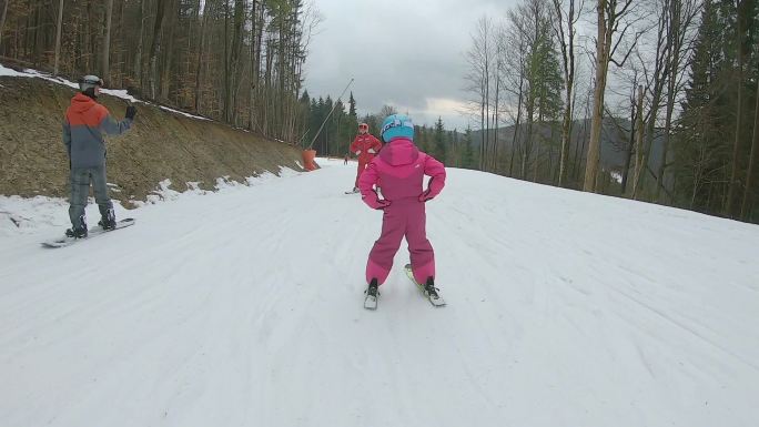 一个小女孩和滑雪教练一起滑雪下山