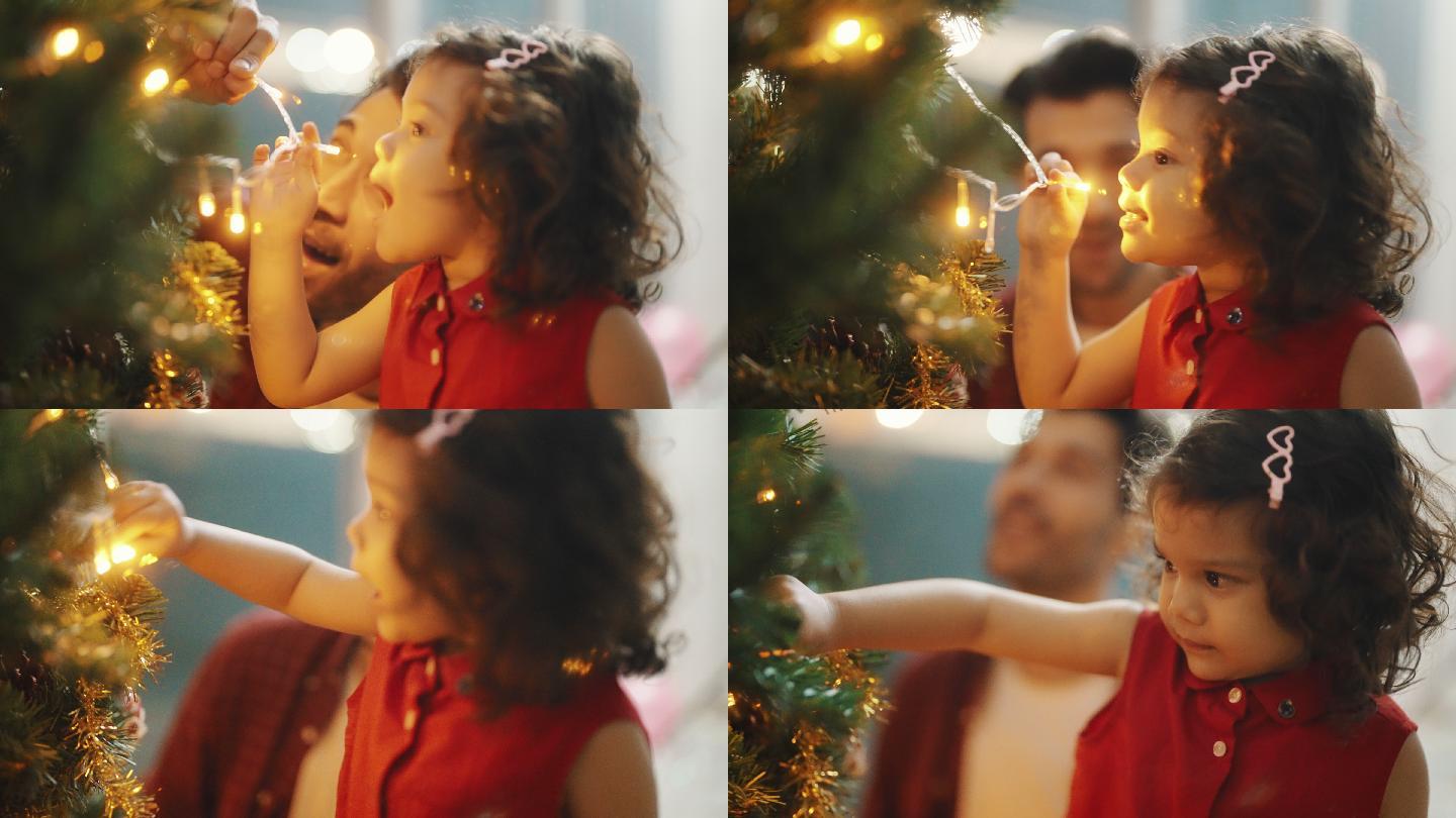 可爱的小女孩和她的父亲在家里装饰圣诞树