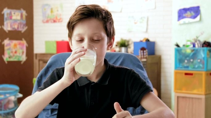 可爱的小男孩喝着一杯牛奶，竖起大拇指