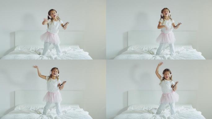 小女孩戴着耳机听音乐，在父母的床上跳舞