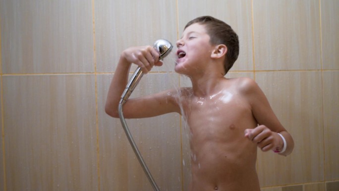 可爱英俊的小男孩在浴室里唱歌跳舞