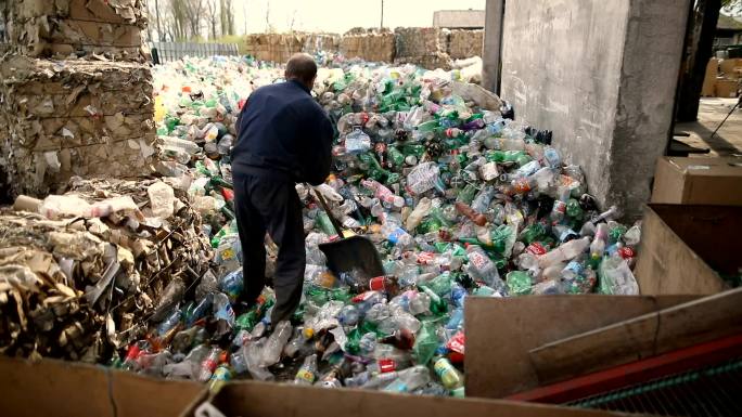 工人用铲子推塑料瓶进行回收