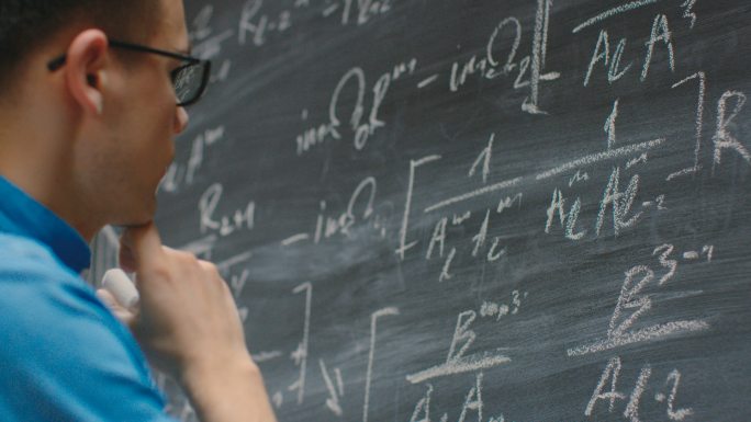 年轻数学家在黑板上写复杂的数学方程/公式