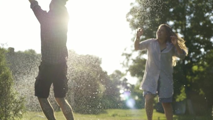 日落时分一对年轻的夫妇在花园里浇水玩耍
