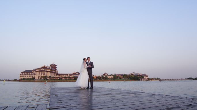 新婚夫妇在湖边栈桥眺望远方