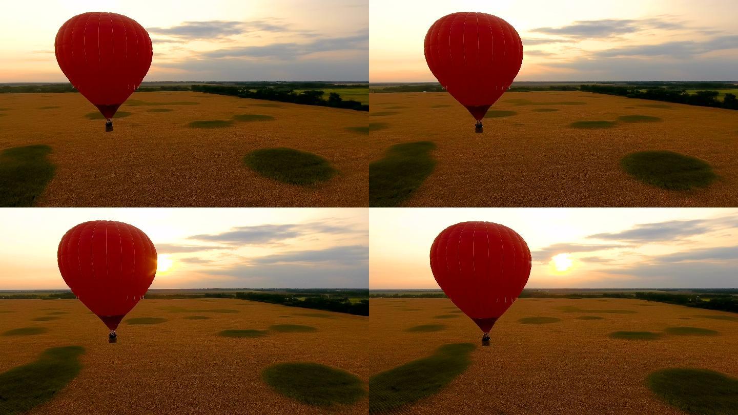 日落时飘过田野的红色热气球