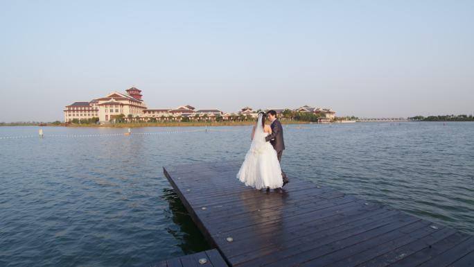 新婚夫妇在湖边栈桥眺望远方
