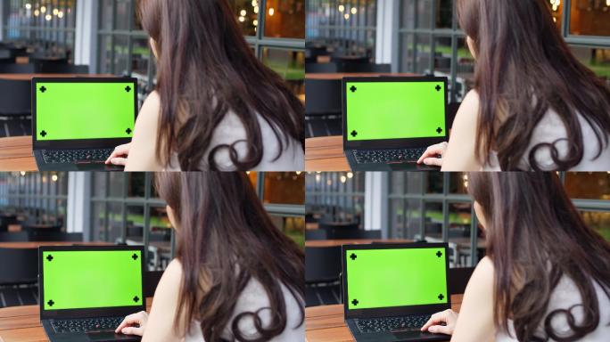 女人看着绿色屏幕的笔记本电脑