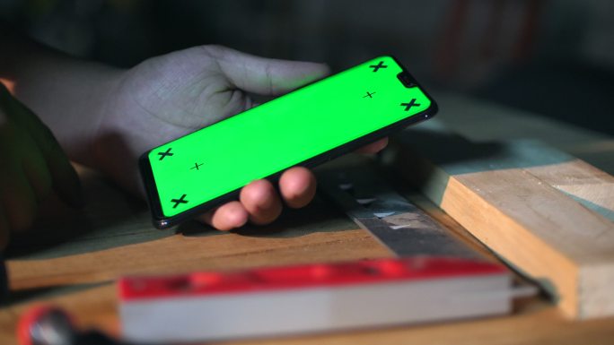 木匠在车间使用绿色屏幕手机