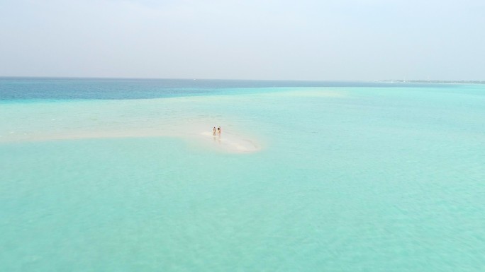 人们站在蓝色海洋环绕的热带海滩上