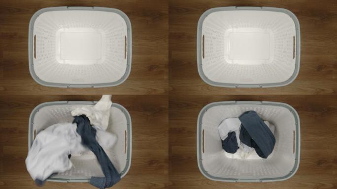 脏衣服落在一个白色的洗衣篮里