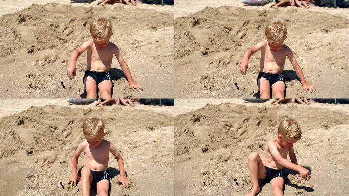 可爱的小男孩坐在海边的沙滩上晒太阳。