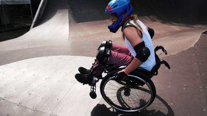 女子坐轮椅在滑板公园做特技