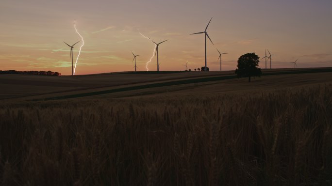 闪电划过布满风力涡轮机的乡村上空