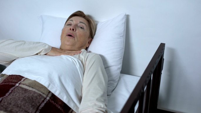 老年女病人躺在病床上请求帮助