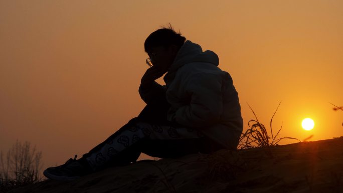 夕阳下坐在山峰上抑郁的男人